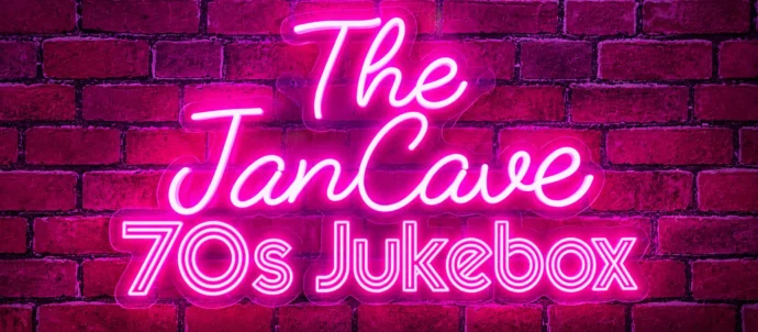 Pink neon sign reading The JanCave 70s Jukebox against a purple brick wall